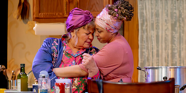 Mother and adult daughter embracing while cooking