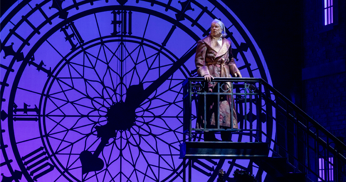 Scrooge on step in front of purple clock face.