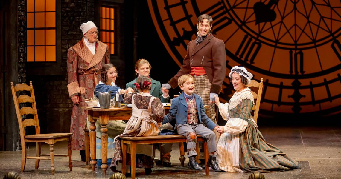 (1st row, L to R) Jocelyn Baum, Hugo Verderame, Kelly Mengelkoch (Mrs. Cratchit), (2nd Row, L to R) Andrew May (Ebenezer Scrooge), Seava Sierra King, Rae Thornburg and Ryan Wesley Gilreath (Bob Cratchit). Photo by Mikki Schaffner.