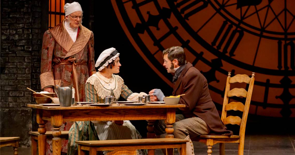 (Front) Kelly Mengelkoch (Mrs. Cratchit), Ryan Wesley Gilreath (Bob Cratchit) and (back) Andrew May (Ebenezer Scrooge) in A CHRISTMAS CAROL at Cincinnati Playhouse in the Park. Photo by Mikki Schaffner.