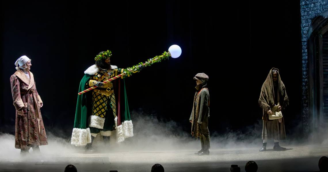 (Left to right) Andrew May (Ebenezer Scrooge), Kenneth Early (Ghost of Christmas Present), Michael Wood (Ignorance) and Chaarvi Iyengar (Want) in A CHRISTMAS CAROL at Cincinnati Playhouse in the Park. Photo by Mikki Schaffner.